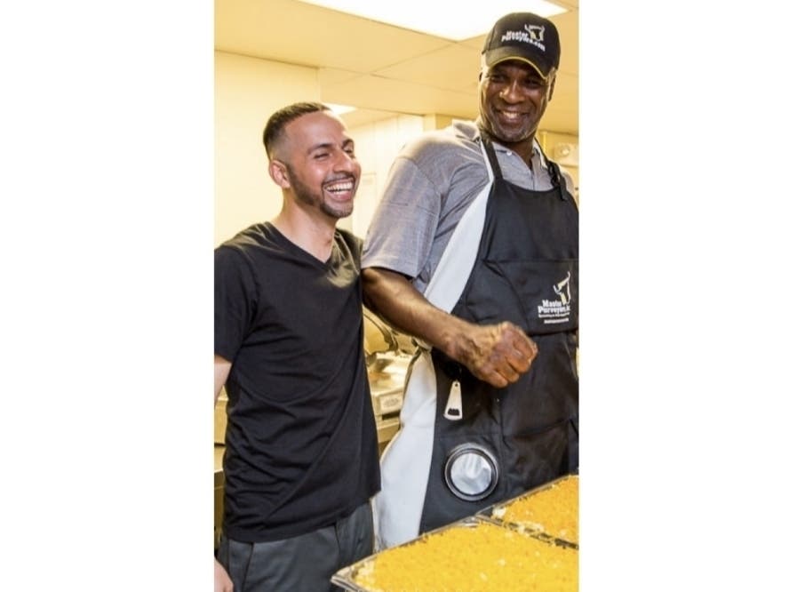 Akhtar Farzaie, owner of Bella Pizza in Hillsborough, with former NBA New York Knick legend Charles Oakley laughing by Oakley's famous mac and cheese.