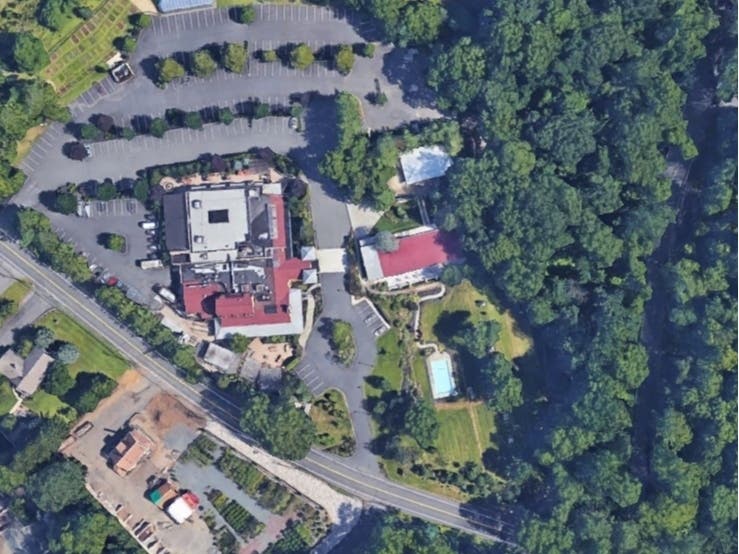 The proposed hotel will be located in the wooded area to the right of the existing hall near Stiles Road.