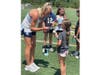 Girls Lacrosse coach signing a ball.