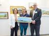 Second Place Artist Andrea Gianchiglia with Commissioners Melonie Marano and Paul Drake holds her painting of Derwood Farm in Hillsborough.