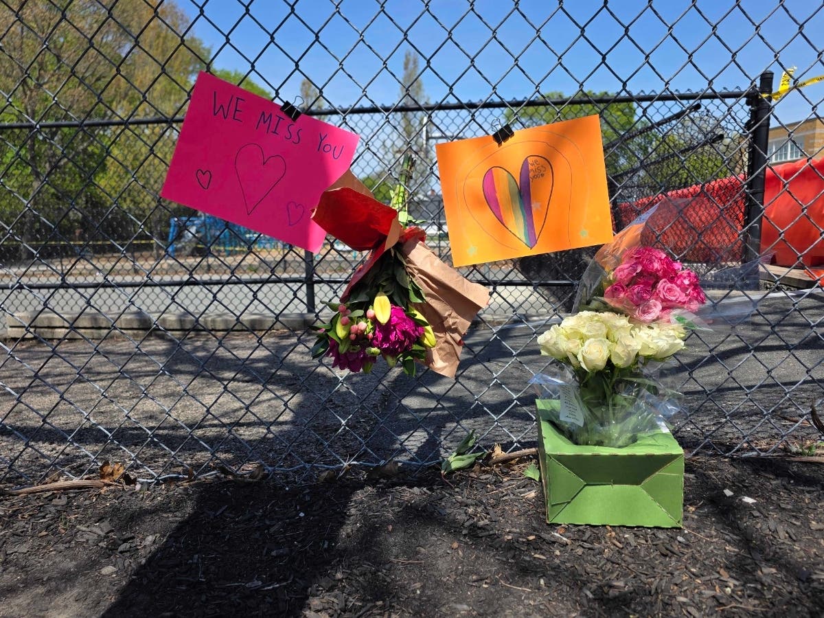 Flowers and handwritten notes hang on the playground fence at the Winthrop School, where a community gathers in grief.