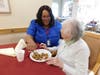Home Health Aide trainee Janis Moore assists an assisted living resident with her meal as part of her hands-on training.