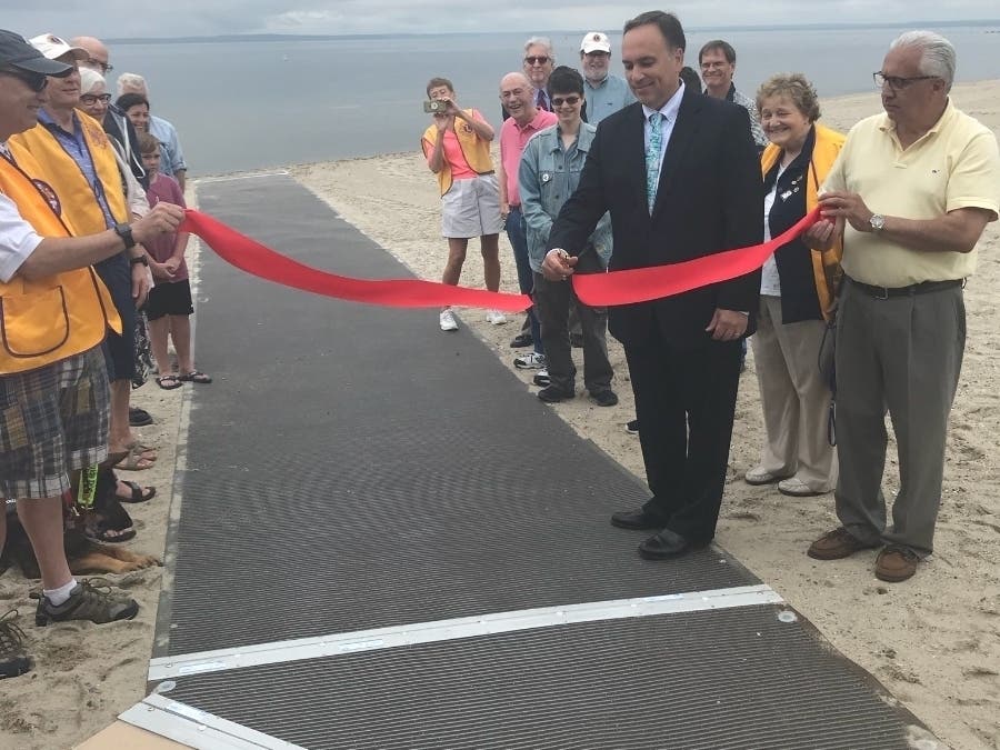 First Selectman Peter Tesei unveils a new beach access mat at Greenwich Point during a recent ribbon cutting ceremony.