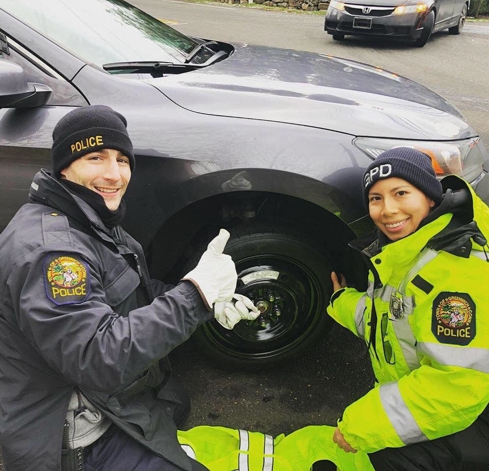 Greenwich Police officers Pat O'Connor and Siuyan Su Ah Sor help a driver in town with a flat tire