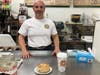 Upper Crust Bagel Company owner Robert Guerrieri stands with a bagel and coffee at his shop on Sound Beach Avenue in Greenwich.