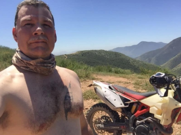 Roberto Camou posted an online photo of himself and his motorcycle in a hilly, open area.
