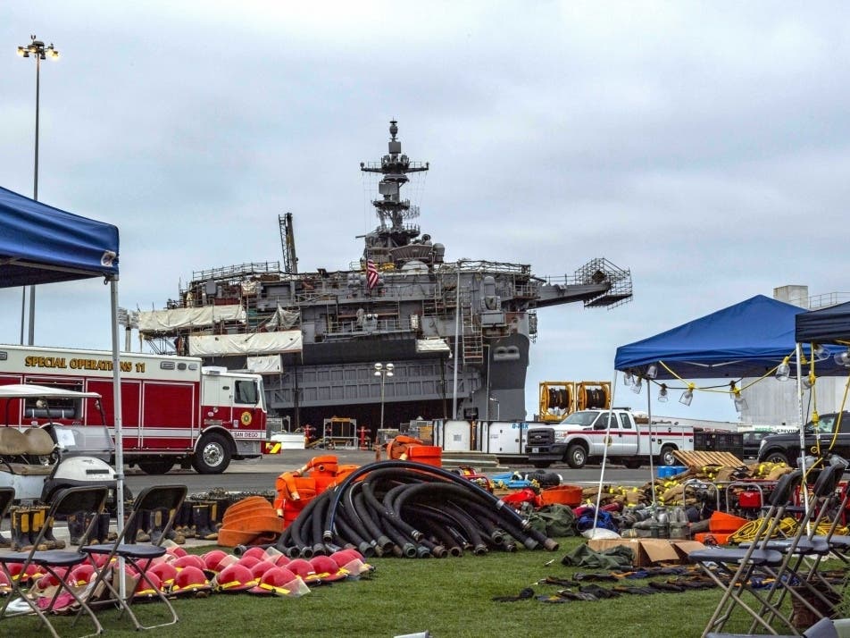 Firefighting gear lies in organized piles for the next firefighting shift at Naval Base San Diego behind the amphibious assault ship USS Bonhomme Richard (LHD 6), July 17.