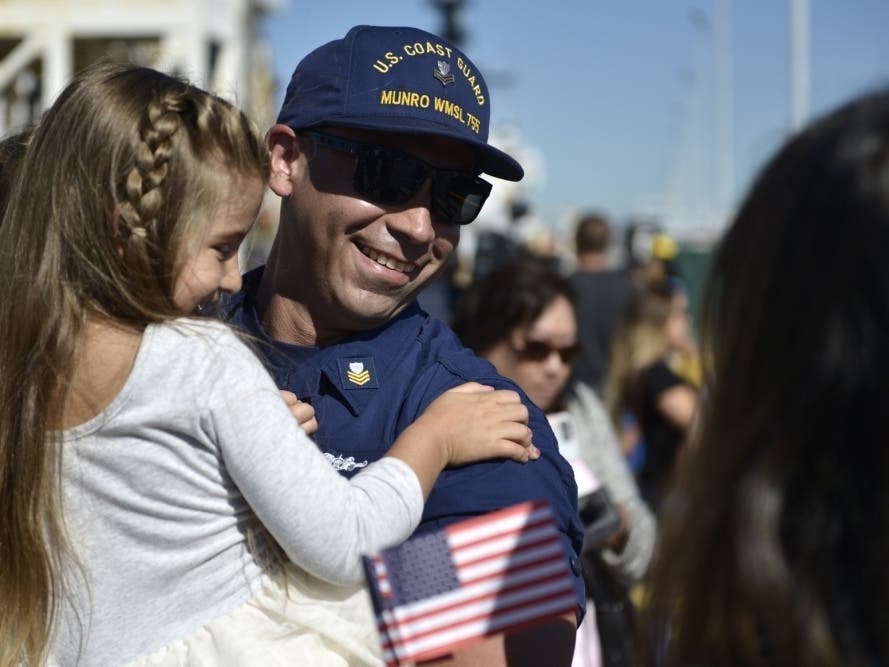 Petty Officer 1st Class Edward Sanchez holds his daughter after returning to home port in Alameda