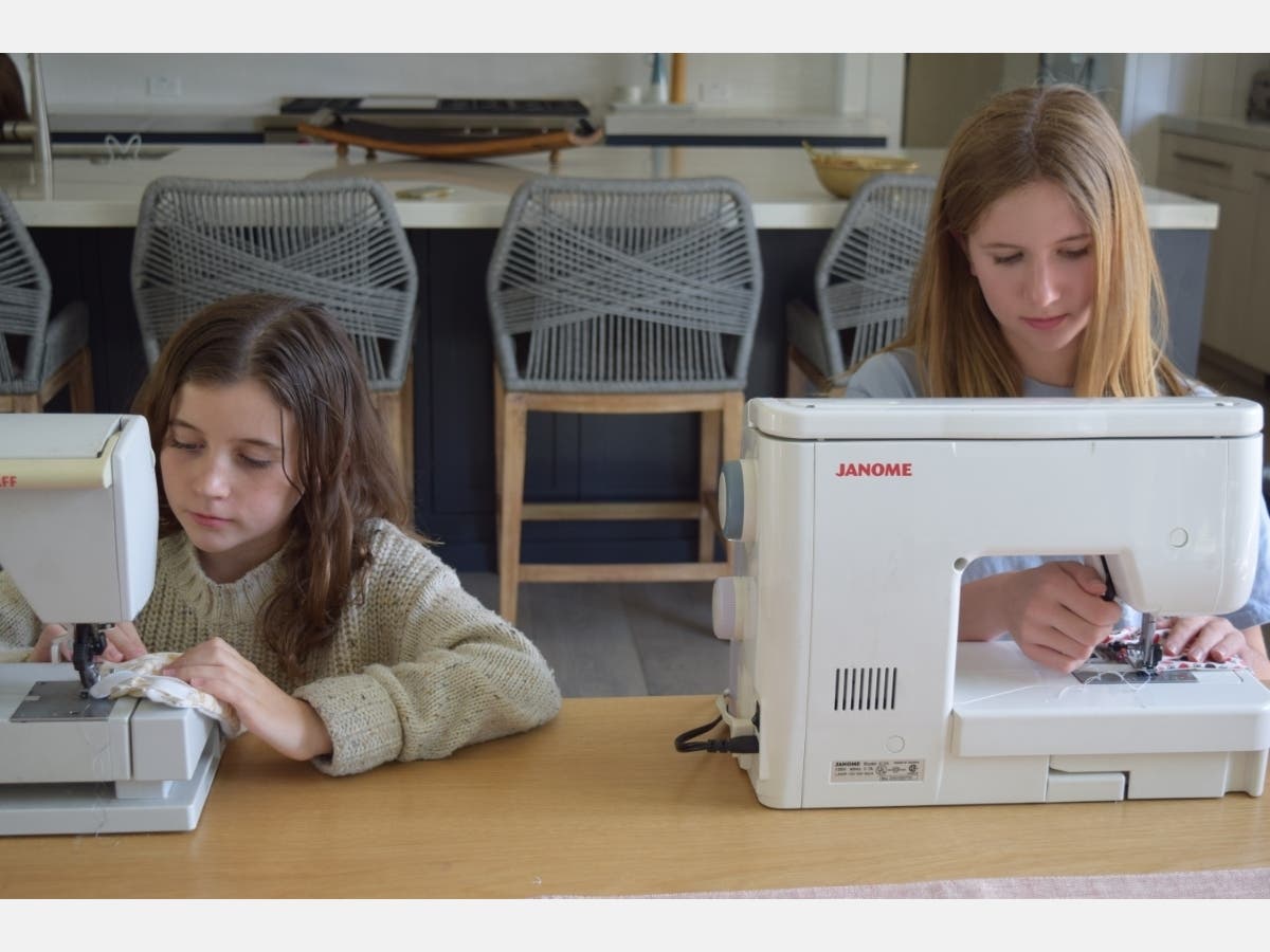 Grace, left, and Audrey Kosla work on masks in the family  room of their family's Orinda home