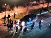 Protesters surround an SUV, holding the occupants prisoner and trying to open the driver's door.