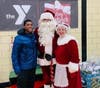 Jahkil Naeem Jackson, founder of Project I am, attended the 2022 NSYMCA Holiday Giveback and takes a photo with Santa and Mrs. Claus
