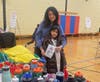 Caption:  Geeta Chennareddy and her daughter Lara, age 7  help pack blessing bags at the North Suburban YMCA’s 7th Annual Holiday Giveback event on December 7th. 