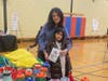 Caption:  Geeta Chennareddy and her daughter Lara, age 7  help pack blessing bags at the North Suburban YMCA’s 7th Annual Holiday Giveback event on December 7th. 
