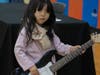 A young girl tries out an electric guitar at the School of Rock table at the NSYMCA Youth Explorer Expo on Sunday, January 12.