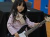 A young girl tries out an electric guitar at the School of Rock table at the NSYMCA Youth Explorer Expo on Sunday, January 12.