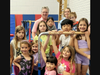 The NSYMCA Gymnastics Team with Howard Schultz, the grantor of the Ruth Schultz Bright Days Fund, poses on the 5-in-1 Bar System donated to the The North Suburban YMCA in Northbrook.