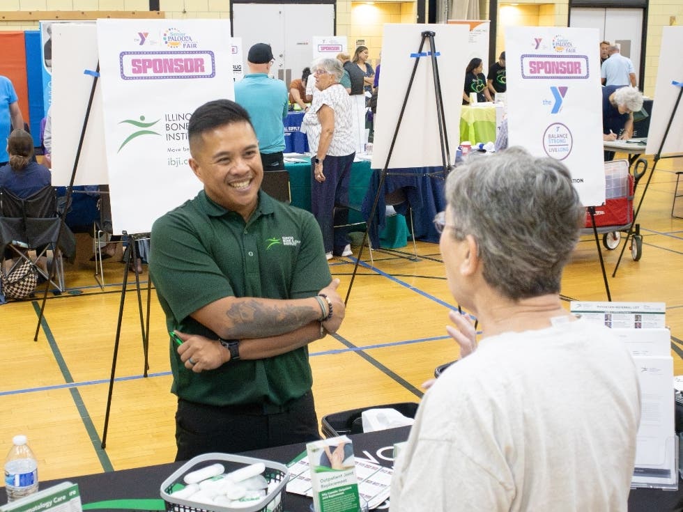 The NSYMCA’s 10th Annual SeniorPalooza Health and Fun Fair featured over 60 vendors including Ryan Caturan from Illinois Bone and Joint Institute, who talks with a guest about the importance of balance and pain free movement.