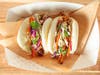 Korean BBQ Bao Buns — Rooted & Wild by Snack House tosses plant-based shredded "meat" in Korean barbecue sauce with pineapple slaw on steamed bao buns.
