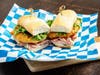 Apple Donut Ham Grinder — Minnesota Farmers Union Coffee Shop stacks battered fried apples with ham and hot honey on a toasted hoagie roll.
