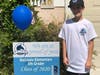 Jake smiles with his yard sign and balloon, sent by Bathgate Elementary School.
