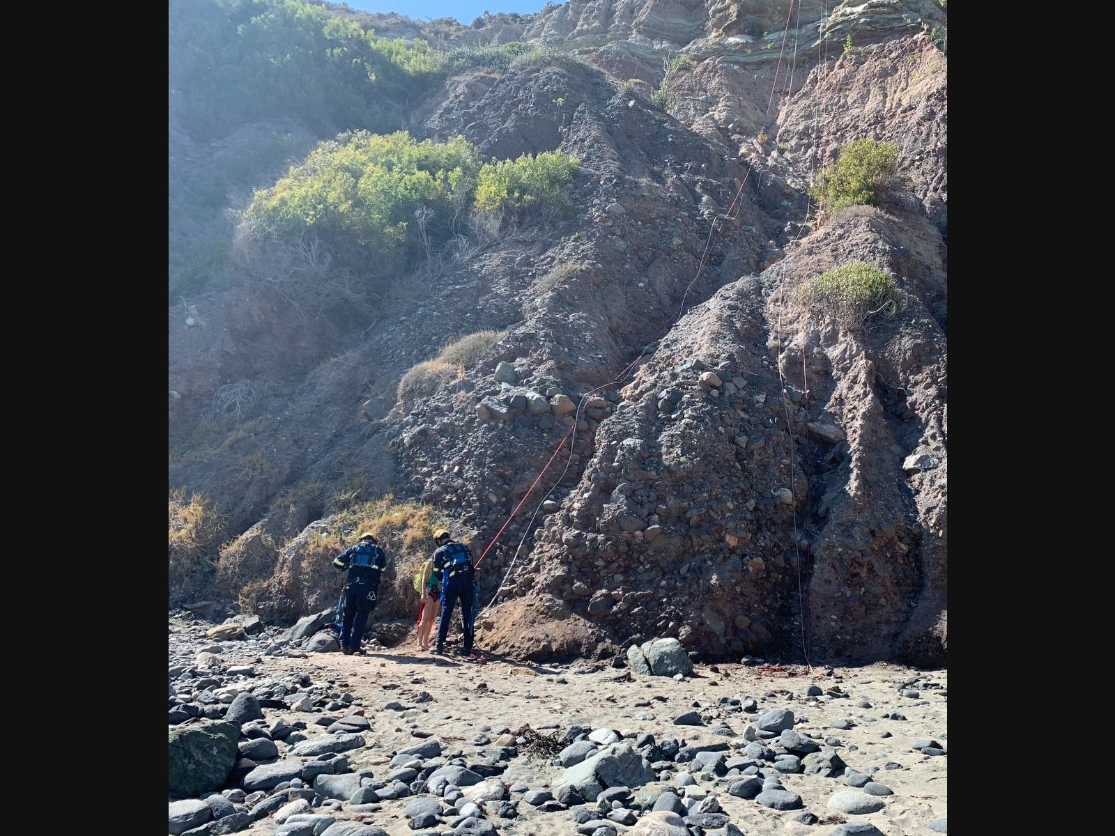Technical rescue firefighters rappelled down the steep cliffs to lend aid to a woman and two children who were trapped above Dana Cove.