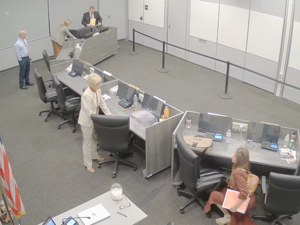 Dr. Melinda Anderson, District 1 Trustee, was seen on video taking her purse and kneeling in front of the vacant desks of two trustees, and placing something underneath.