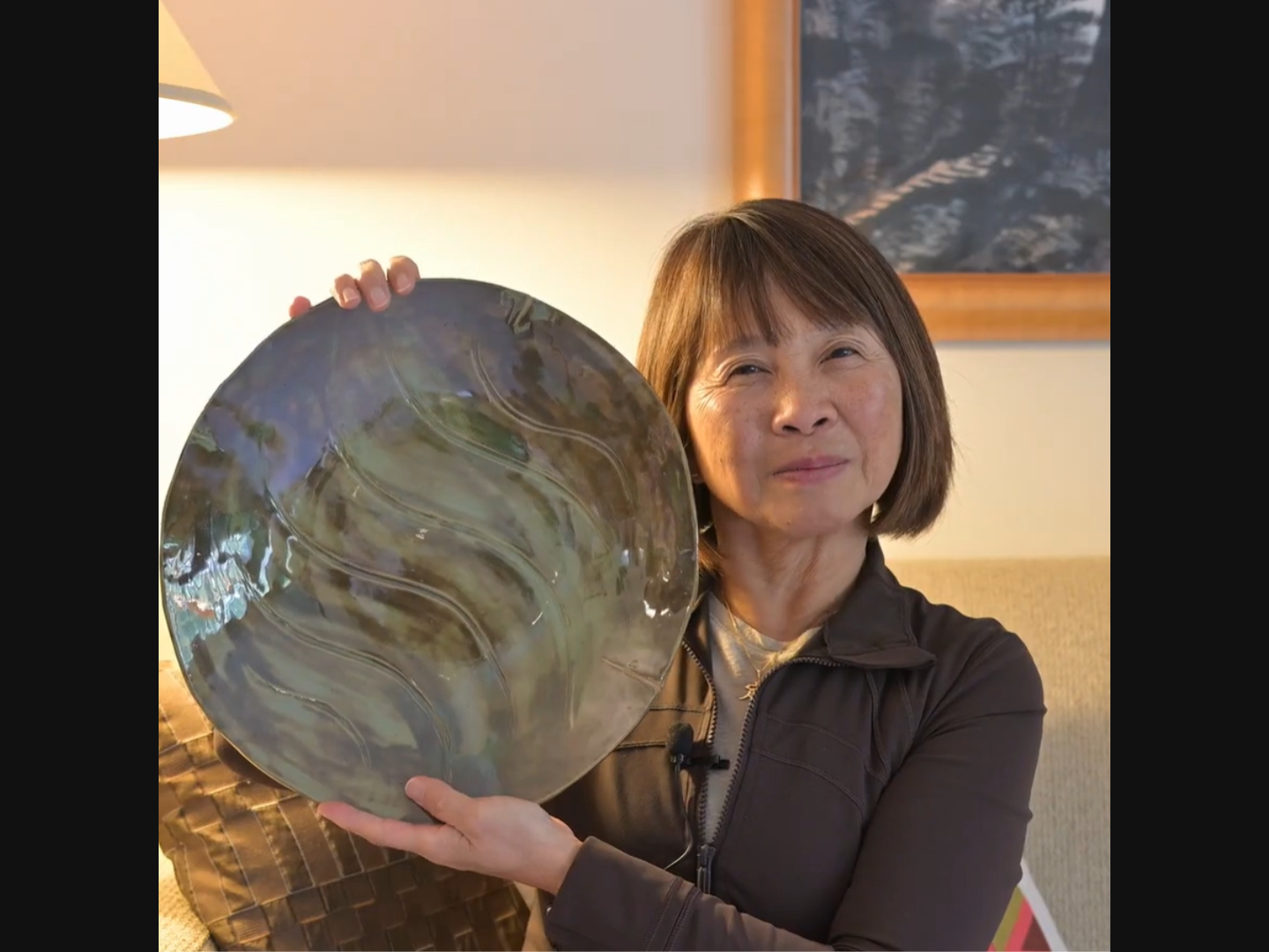 Alice Chow proudly displays one of her ceramic works during videotaping of her Life Stories Program produced by a videography team provided by North Shore Senior Center.