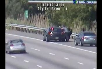 A Pennsylvania State Police trooper speaks to the naked man in the backseat of his cruiser Monday morning on I-95.