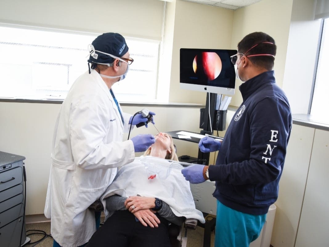 Dr. Rosen (left), Nancy (center), and Dr. D Souza (right). Rosen is using an endoscope to place the platelet-rich plasma (PRP) on the olfactory nerve in Nancy's nose. The PRP is mixed with a dissolving sponge and is a painless procedure.