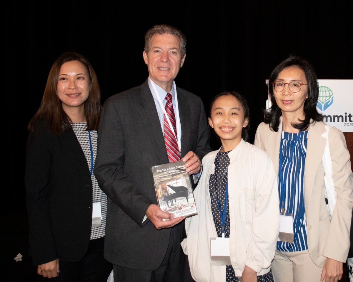 Representatives of the Action Alliance to Redress 1219 present former U.S. Ambassador-at-large for International Religious Freedom Sam Brownback, co-chair of the IRF Summit 2021, with two books about human rights, justice, and religious freedom.
