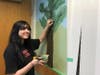 Reading Memorial High School student Jahnavi Patel working on a mural inside the newly decorated public interview room.