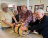 L to R: Cathy Dangona, Dennis Scaglione and Barbara Cubberly roll up a completed sleeping bag, filled with winter goodies.