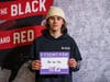 Devils center Jack Hughes holds a placard in honor of his papa and nana