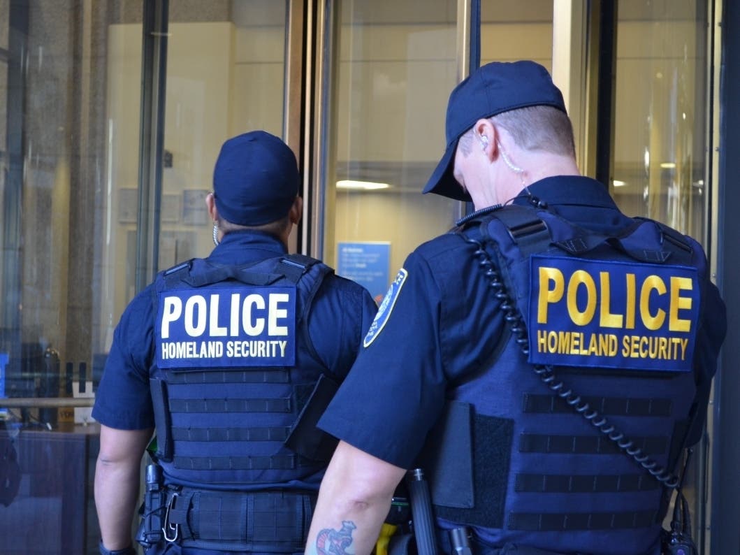DHS officers enter a downtown Seattle office building housing ICE offices in July 2018.