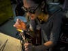 Schafer uses a torch to shape a piece of glass that will eventually become a spot on a mushroom sculpture. 