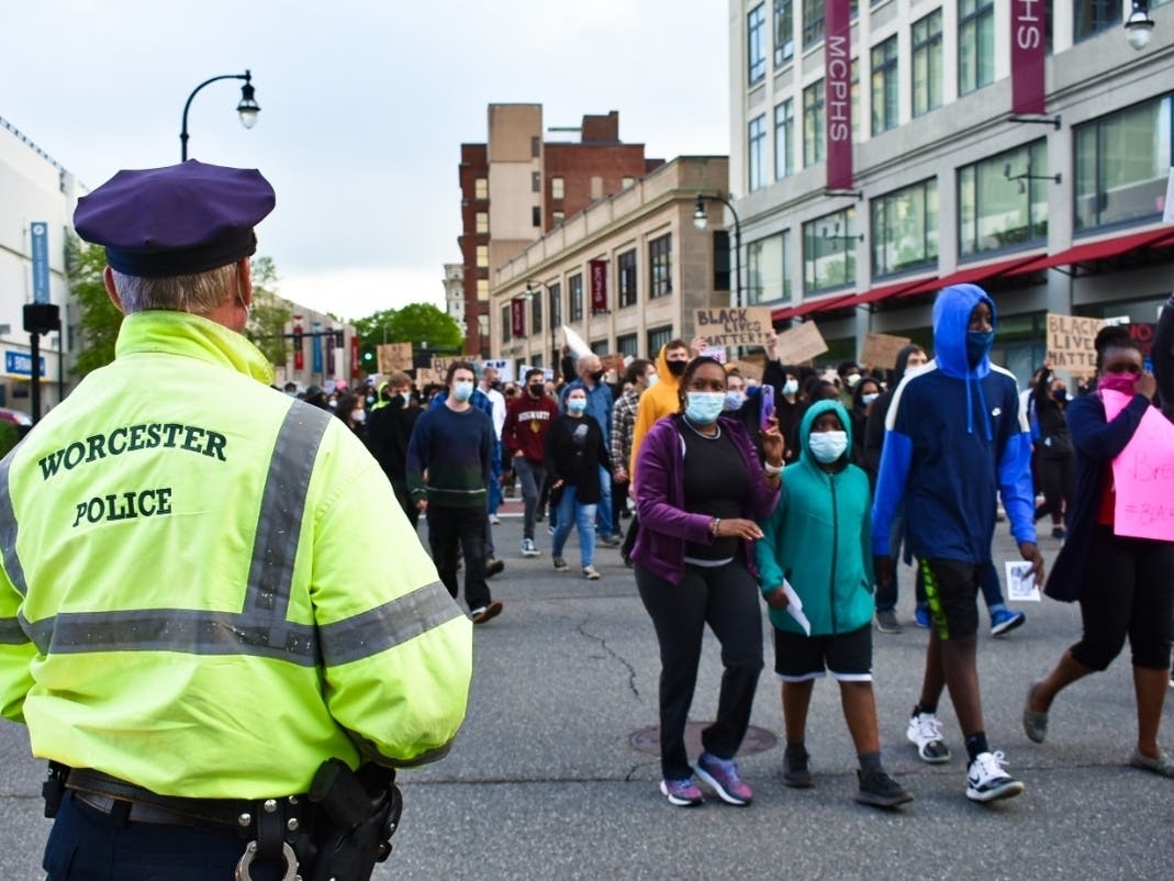 A Worcester police officer watches demonstrators march down Commercial Street during a June 1 protest. 