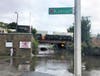 Bystanders watch ongoing flooding near Cambridge and Kansas streets. A car was stuck under the bridge with the water line near its roof. 