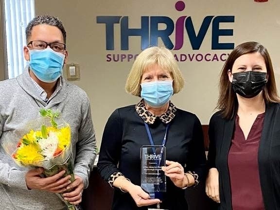 Thrive Support & Advocacy CEO Sean Rose (l) and COO President Stacey Forrest (r) present Marlborough Hospital​ Marketing and Communications​ VP Ellen Carlucci with the “Standing Ovation Award.”