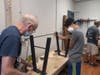 DoodleBug Workshop volunteer and participant attached legs to a table that was made in the Workshop