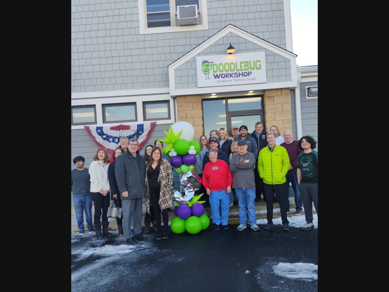 Wheaton Mayor Phil Suess (left, front), DoodleBug Workshop Executive Director Sarah Starke (r of Mayor), Workshop participants and supporters celebrate the 5th anniversary of DoodleBug's 314 S. Main Street, Wheaton location in February, 2025.