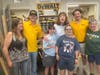 DeWalt representatives Ethan Imlach (left) and Liam Poe (right) along with DoodleBug Workshop executive director Sarah Starke (left) and DoodleBug Workshop participants in front of the DeWalt tool display in the woodworking side of the DoodleBug building.