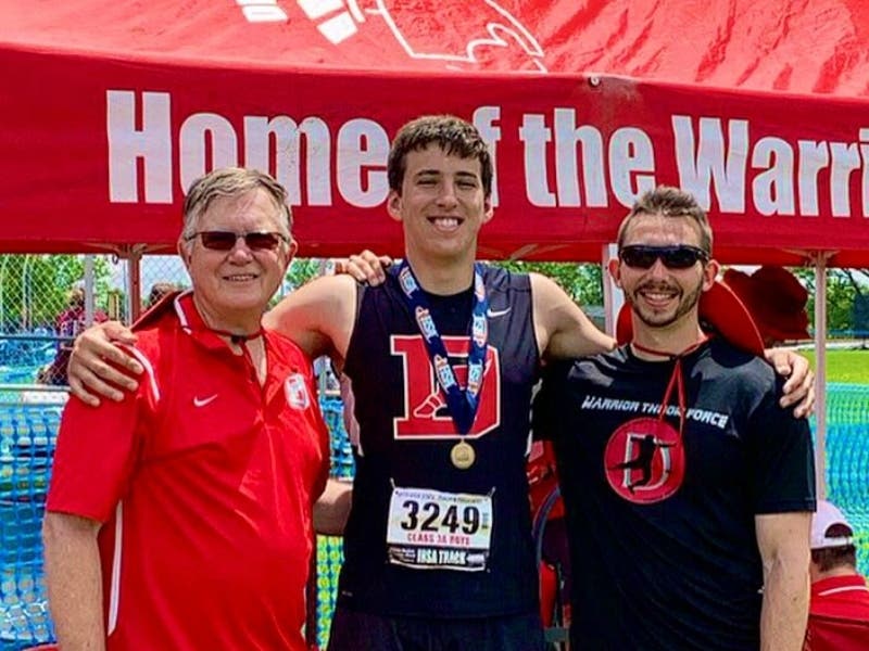 Sam Liokumovich is flanked by coaches Cody Foerch, left, and Kip Gasper after winning the IHSA Class 3A shot put final.