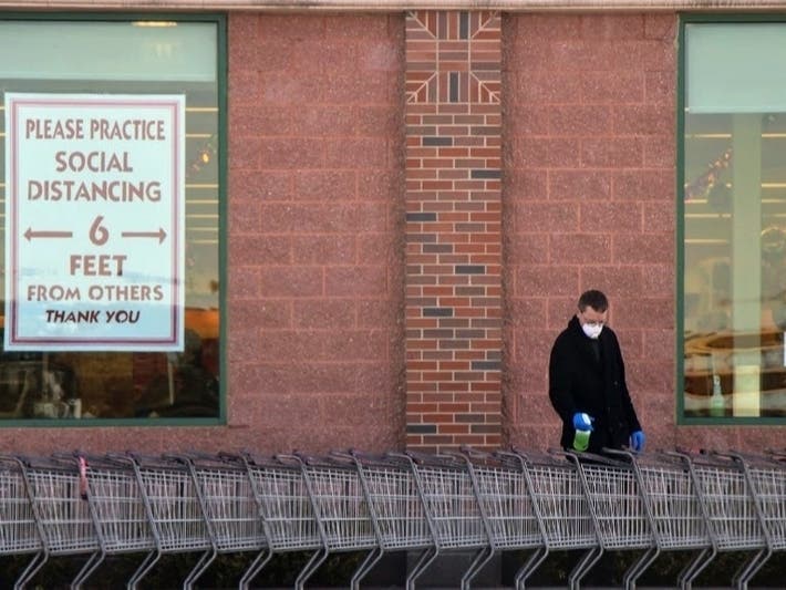 A grocery store worker disinfects a shopping cart. Black and Latino workers are less likely to be able to work from home, putting them at higher risk of exposure to the coronavirus, according to public health experts.