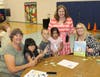 Troy Cronin Elementary School Principal Jill Howard (with book) and Assistant Principal Katie Hogan with one of the grandparents and three students. The families worked on tangram puzzles during the school’s recent Grandparents’ Day.