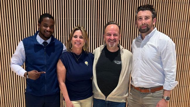 A young African American male students poses with event panelists, a woman and two other men