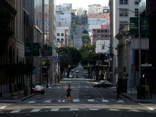 A man runs across a near-empty Montgomery Street in San Francisco. A new analysis by Unacast grades each state and county on how well its residents are practicing social distancing