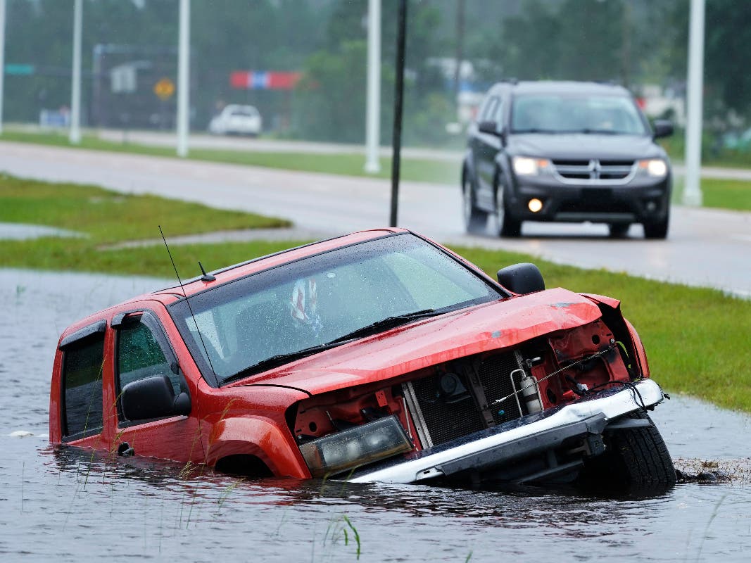 An abandoned vehicle is half submerged in a ditch next to a near flooded highway as the outer bands of Hurricane Ida arrive Sunday, Aug. 29, 2021, in Bay Saint Louis, Miss.