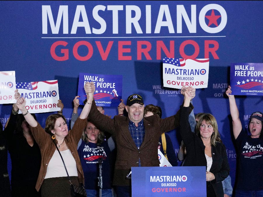 Pennsylvania Republican gubernatorial candidate Doug Mastriano, his wife Rebecca Mastriano, left, and running mate Carrie Lewis DelRosso, right, hold hands high on stage with supporters during his election night campaign gathering at the Penn Harris Hotel