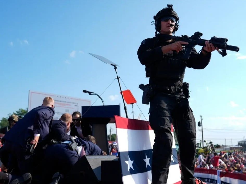 Republican presidential candidate and former President Donald Trump is covered by U.S. Secret Service agents at a campaign rally as an officer stands guard.