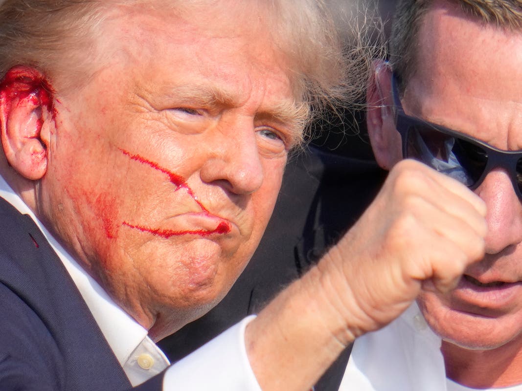 Republican presidential candidate former President Donald Trump gestures while surrounded by U.S. Secret Service agents as he is helped off the stage at a campaign rally in Butler, Pa., Saturday, July 13, 2024.